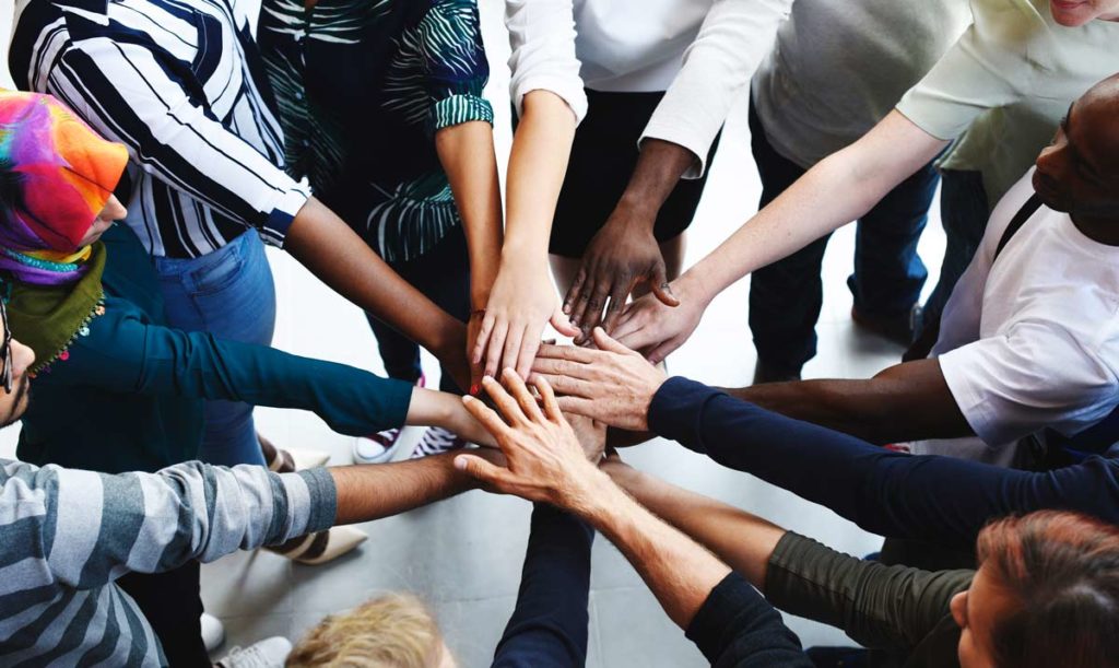 Diverse group of people putting hands in a circle